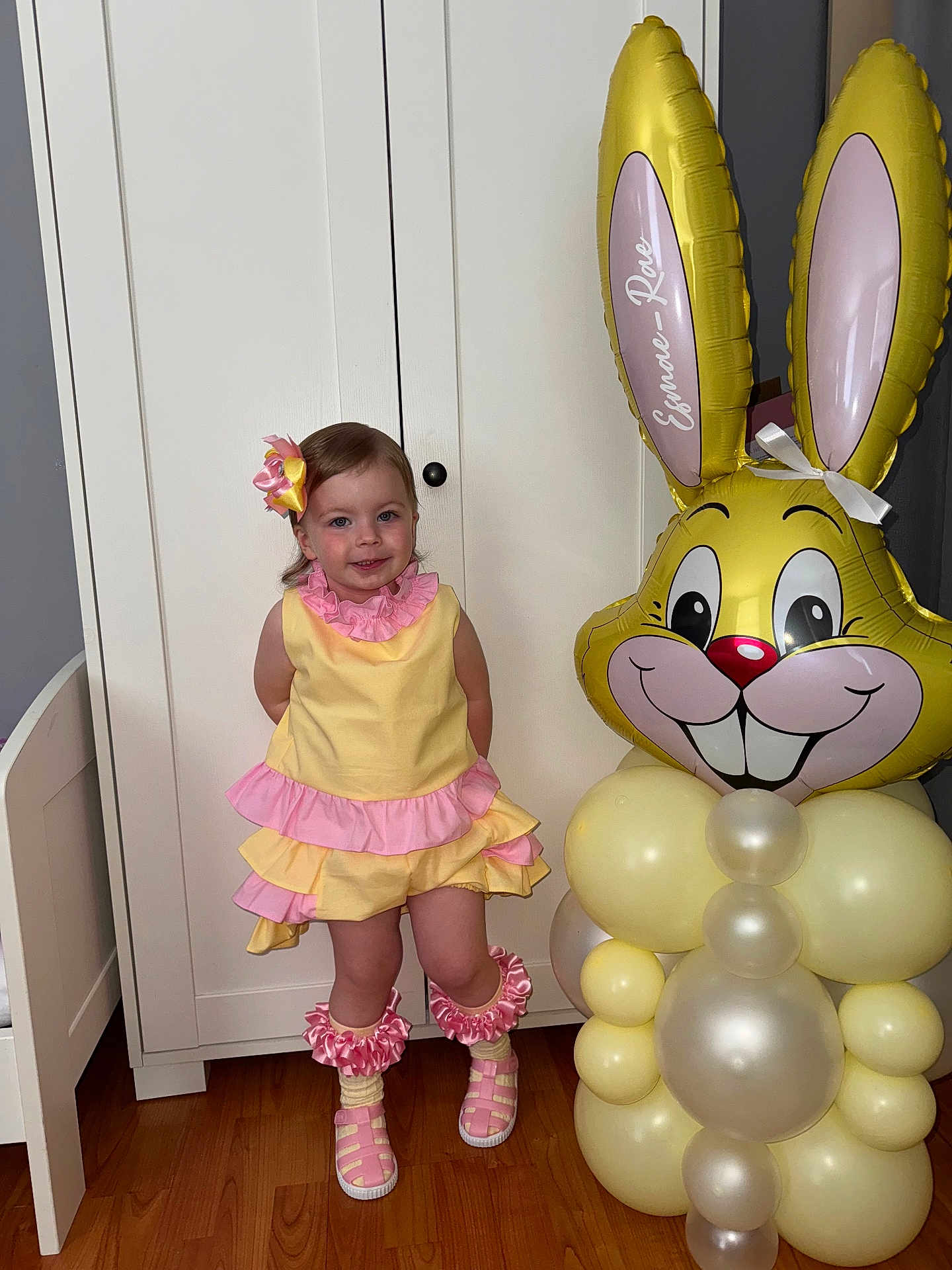 Esmae-Rae joined the competition — help win amazing prizes! toddler, child, yellow_dress, pink_ruffles, balloon_bunny, indoor, wooden_floor, cabinet, footwear, bow, leg_warmers, smile, cute_pose, party_decoration, balloons, happy, person, ribbons, pink_shoes, home