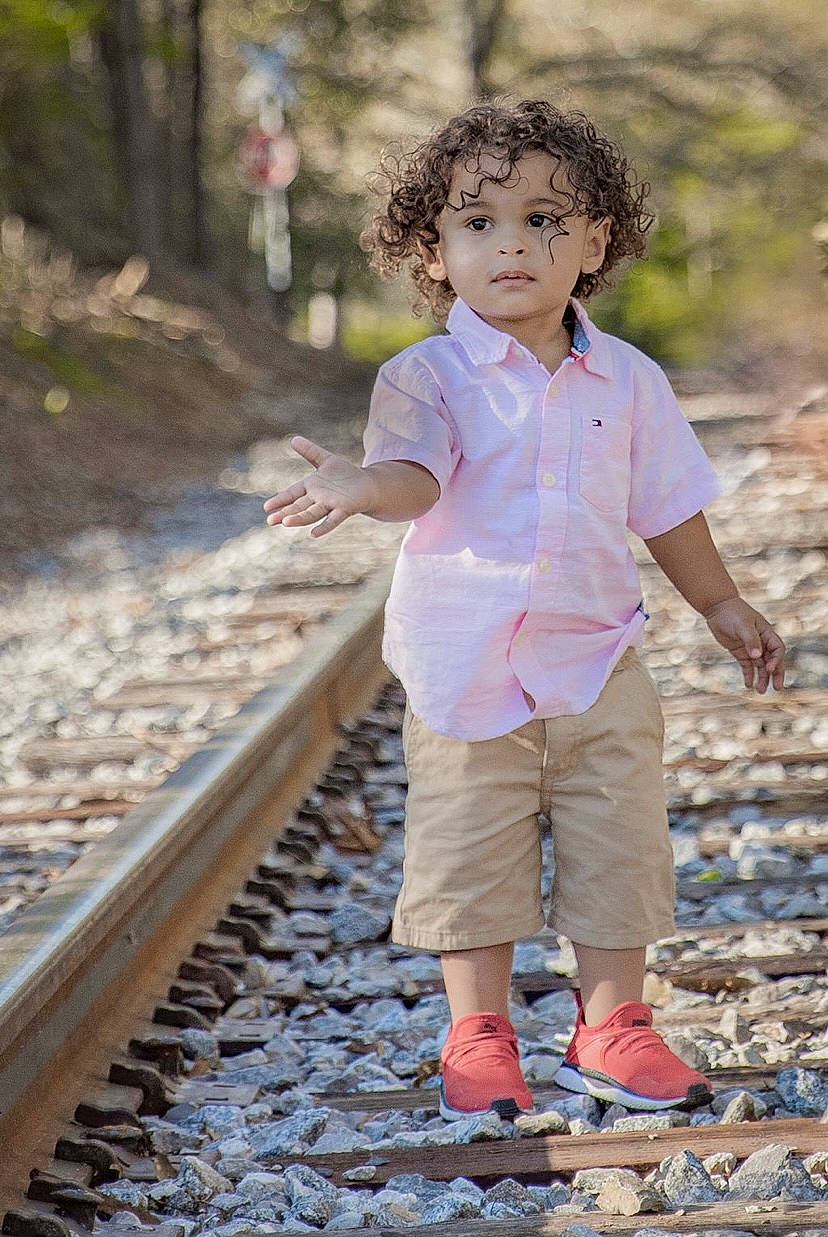 Kylin is registered to the contest to win money with this photo: child, denim, eye, face, forest, fun, grass, hair, happy, head, leaf, leisure, people_in_nature, person, plant, rolling, smile, toddler, track, tree