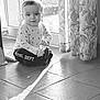toddler, child, indoor, floor, tile, curtains, window, glass_door, sunlight, shadow, long_sleeves, pants, patterned_clothing, sitting, baby, smiling, portrait, home, bright, young_child