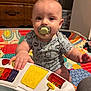 Tatum joined the competition — help win amazing prizes! baby, pacifier, toy, colorful, quilt, playtime, indoor, child, furniture, wood, patterned_clothing, infant, hand, face, eyes, mouth, sitting, expression, room, curious