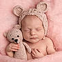 newborn, baby, sleeping, knitted_hat, teddy_bear, crocheted_toy, pink_blanket, soft_texture, cute, infant, peaceful, cozy, hand, portrait, child, adorable, bedtime, rest, warm, snuggle