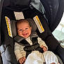 baby, smiling, car_seat, infant, white_clothing, knitwear, safety_harness, happy, child, indoor, cute, person, seat, black, fabric, head_support, foot, baby_girl, portrait, childcare
