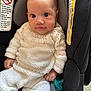baby, child, infant, car_seat, knitted_clothing, pacifier, white_outfit, face, eyes, hand, safety_warning, seat_belt, portrait, indoors, cute, smile, young_child, seated, closeup, person