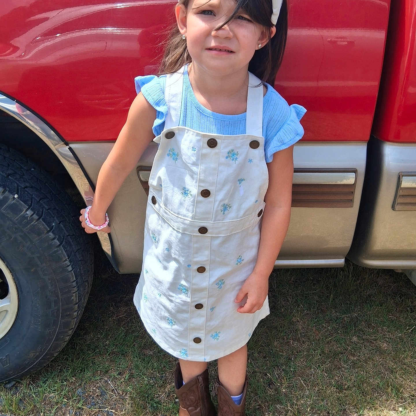 Athena Allred joined the competition — help win amazing prizes! child, girl, dress, headband, boots, standing, outdoor, grass, vehicle, tire, red, white, blue, face, hair, earrings, bracelet, sunlight, expression, casual