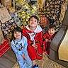 child, children, christmas_tree, pajamas, presents, holiday, indoor, smiling, happy, carpet, decorations, festive, family, gifts, living_room, cozy, celebration, young, sitting, cute