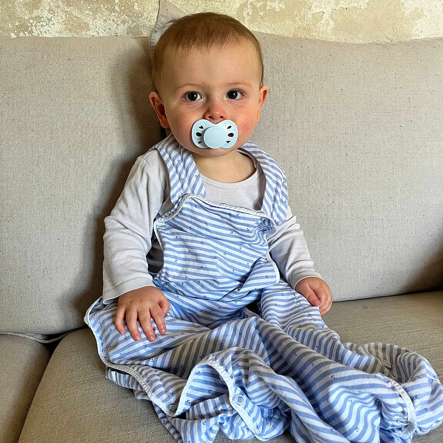 Eden participe au concours pour gagner de l'argent avec cette photo : baby, beige, blue, casual, child, comfortable, couch, cute, fabric, home, indoor, infant, long_sleeves, looking_at_camera, pacifier, portrait, sitting, striped_clothing, white, young_child