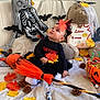 baby, child, halloween, costume, skeleton, teddy_bear, pumpkin, autumn_leaves, pinecones, broomstick, toy, decorations, festive, indoor, cute, sitting, black_clothing, orange, holiday, playful