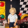 Caleb joined the competition — help win amazing prizes! blue_shirt, checkered_flag_pattern, child, curly_hair, indoor, navy_shorts, oil_can, photography, portrait, red_star_light, retro_theme, route_66_sign, serious_expression, stop_sign, toddler, toy_car, traffic_light, vintage_sign, wooden_crate, yellow_tire