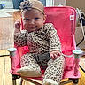 baby, child, leopard_print, onesie, headband, flower, pink_chair, indoor, wooden_floor, smile, happy, cute, person, seated, footwear, belt, toy_chair, infant, home, cozy