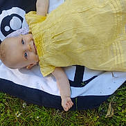 Ysaline participe au concours pour gagner de l'argent avec cette photo : baby, blanket, blue_eyes, child, clothing, cute, grass, greenery, happy, infant, lying_down, nature, outdoor, pattern, portrait, resting, small_flowers, soft_light, summer, yellow_dress