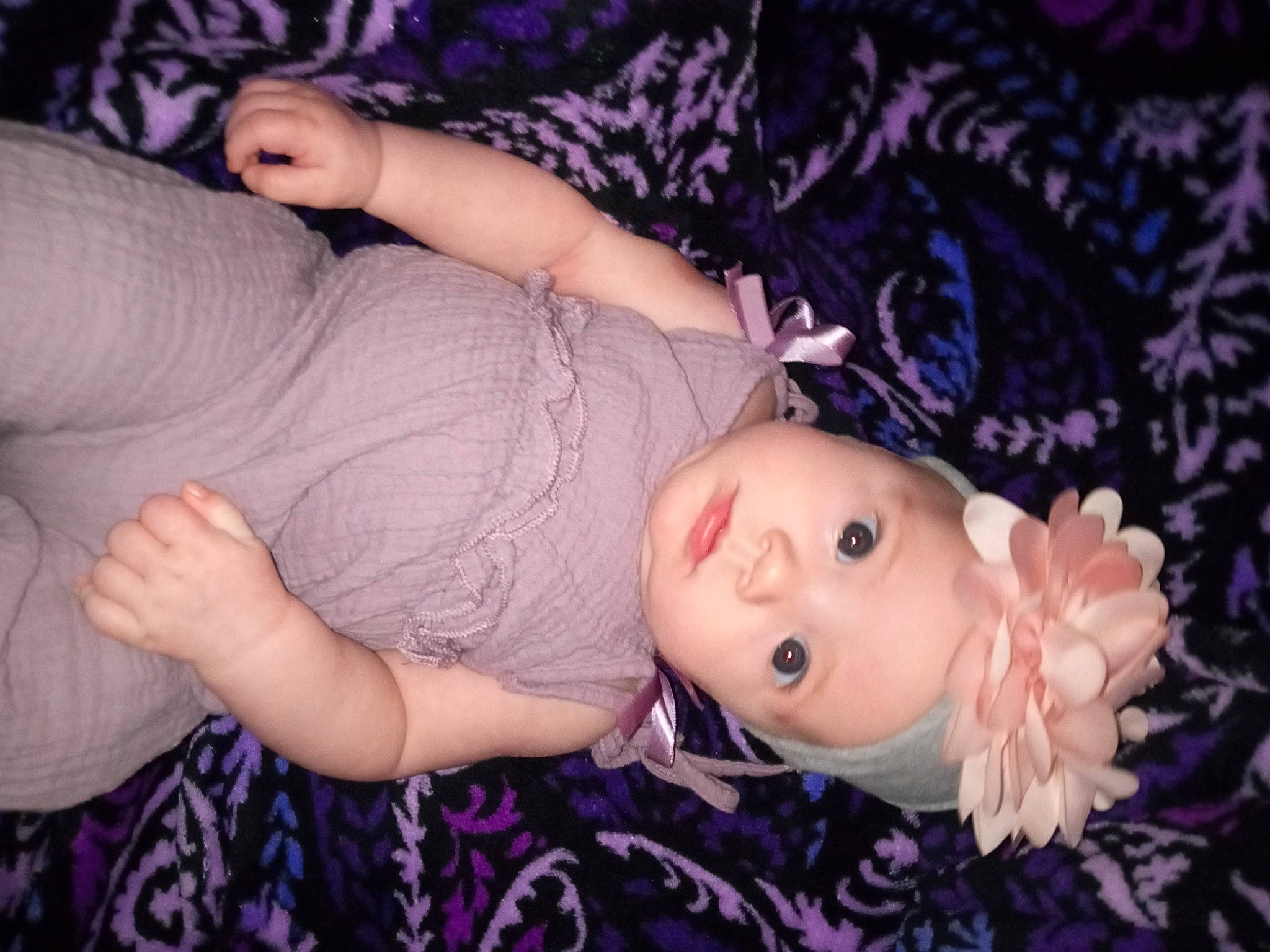 Wrenleigh is registered to the contest to win money with this photo: arm, baby_toddler_clothing, cheek, child, doll, eyelash, grass, hand, headgear, headwear, human_body, iris, lip, pattern, person, pink, plant, purple, skin, toddler