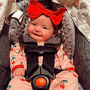 Tatum is registered to the contest to win money with this photo: baby, infant, child, headband, bow, smile, car_seat, harness, onesie, cherry_pattern, canopy, blanket, plush_padding, seat_cushion, cozy, portrait, red_accessory, pink_clothing, nursery_print, happy_expression