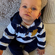 Nathanaël a rejoint le concours — aidez-le/la à gagner de superbes lots ! baby, child, blue_eyes, striped_clothing, navy_blue, white_clothing, teddy_bear_patch, sitting, plush_cushion, soft_texture, indoor, portrait, cute, infant, young_child, hands, feet, close_up, casual_wear, expression