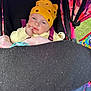 baby, stroller, yellow_hat, blanket, pacifier, child, infant, colorful, outdoor, clothing, face, hand, seatbelt, toy, person, portrait, cute, expression, warm_clothing, resting