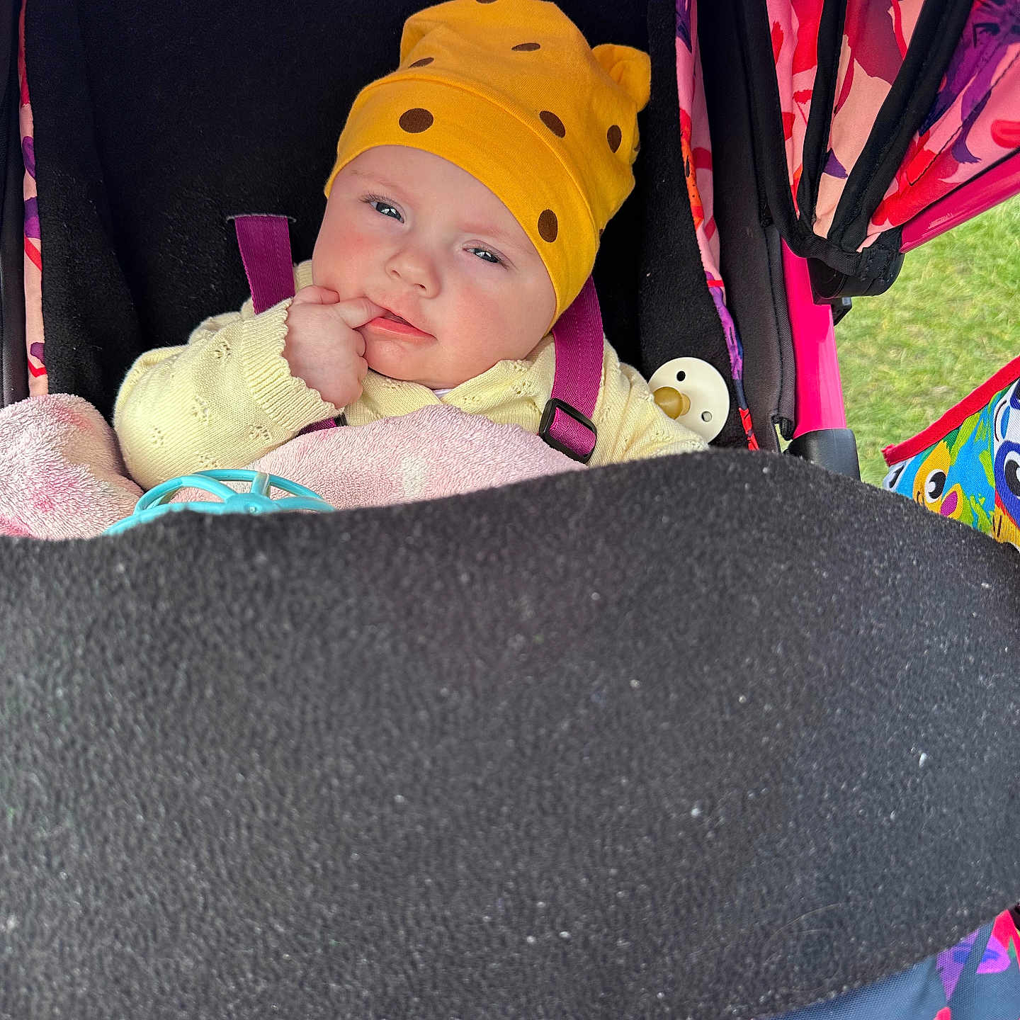 Eva joined the competition — help win amazing prizes! baby, blanket, child, clothing, colorful, cute, expression, face, hand, infant, outdoor, pacifier, person, portrait, resting, seatbelt, stroller, toy, warm_clothing, yellow_hat