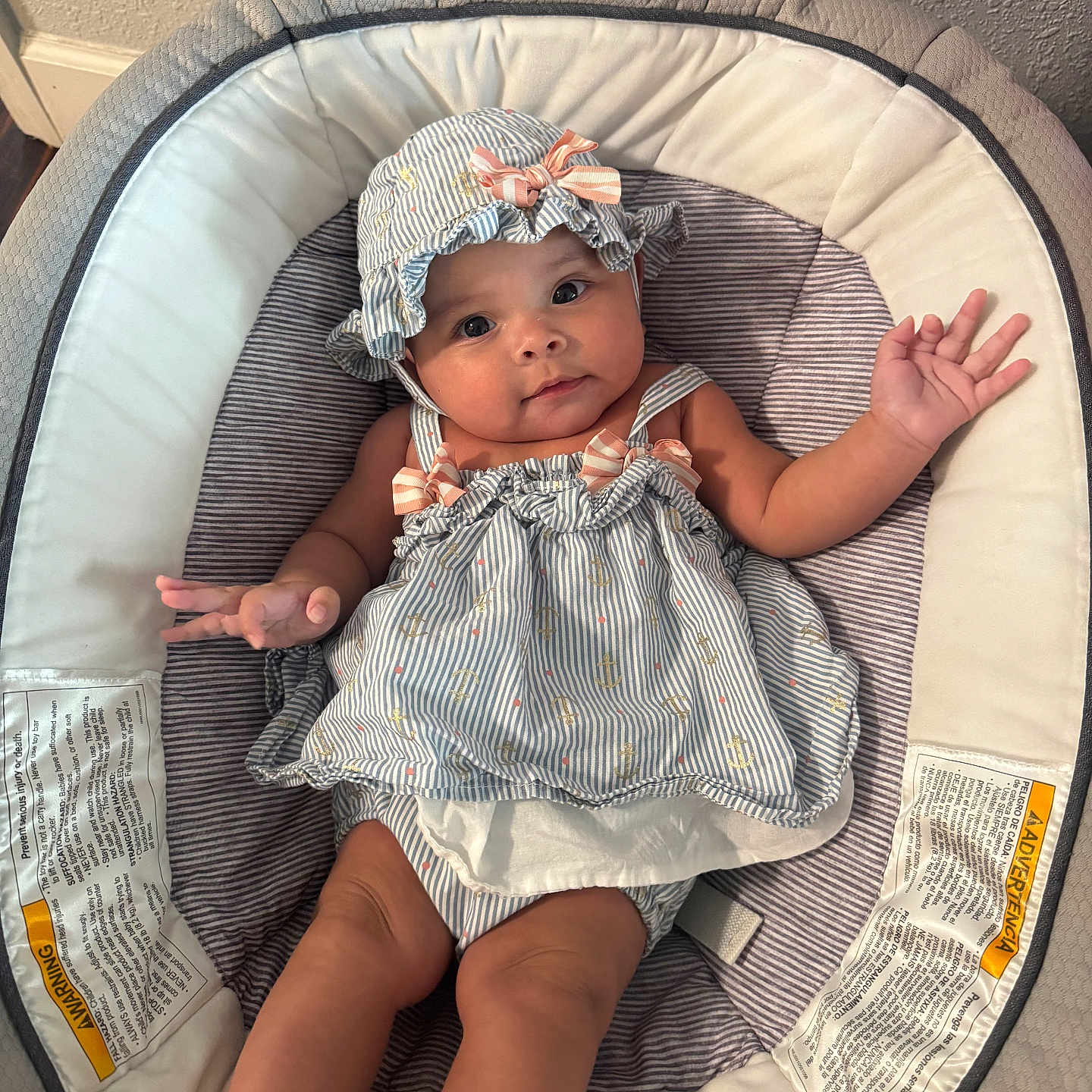 Isabella is registered to the contest to win money with this photo: baby, baby_seat, blue, bonnet, child, clothing, comfortable, cushion, cute, expression, face, hands, indoors, infant, legs, portrait, relaxing, skin, striped, white