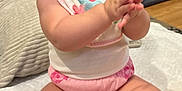 Yazmine joined the competition — help win amazing prizes! baby, child, smiling, clapping, curly_hair, bib, pink_diaper, toy_ball, indoor, floor, happy, cute, person, infant, sitting, soft_surface, home, playful, chubby_legs, closeup