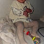Kym participe au concours pour gagner de l'argent avec cette photo : baby, child, infant, knitted_vest, pacifier, toy, rattle, tights, sitting, soft_surface, blurred_background, cozy_clothing, patterned_clothing, indoor, cute, calm, curious, hands, face, head