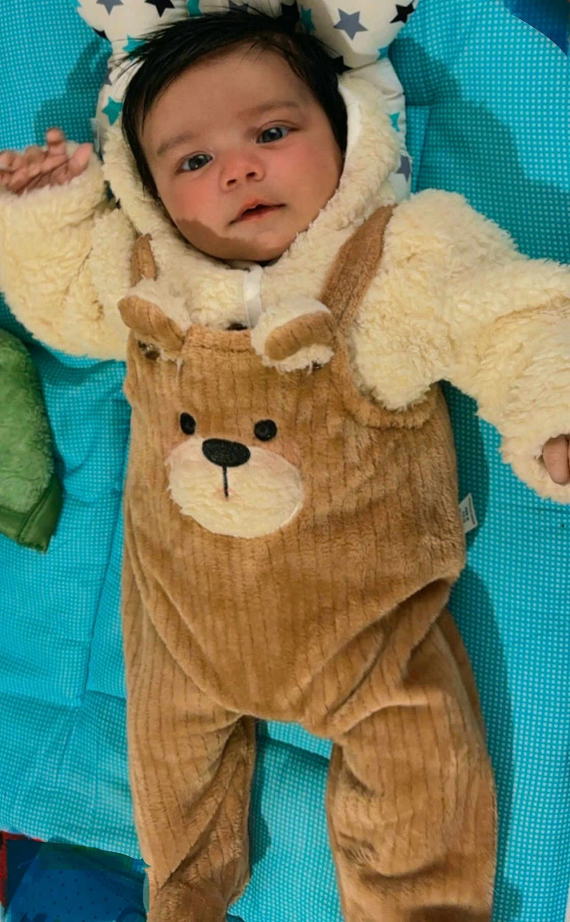Triyansh joined the competition — help win amazing prizes! baby, infant, child, face, cute, clothing, onesie, bear_theme, plush, soft_texture, blue_mat, pillow, stars, lying_down, indoors, portrait, expression, young_child, warm_clothing, cozy