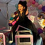 child, girl, black_dress, balloons, birthday_party, number_2_balloon, gift_boxes, table, tent, smiling, happy, celebration, curly_hair, bow, colorful, party_decorations, indoors, person, young, festive