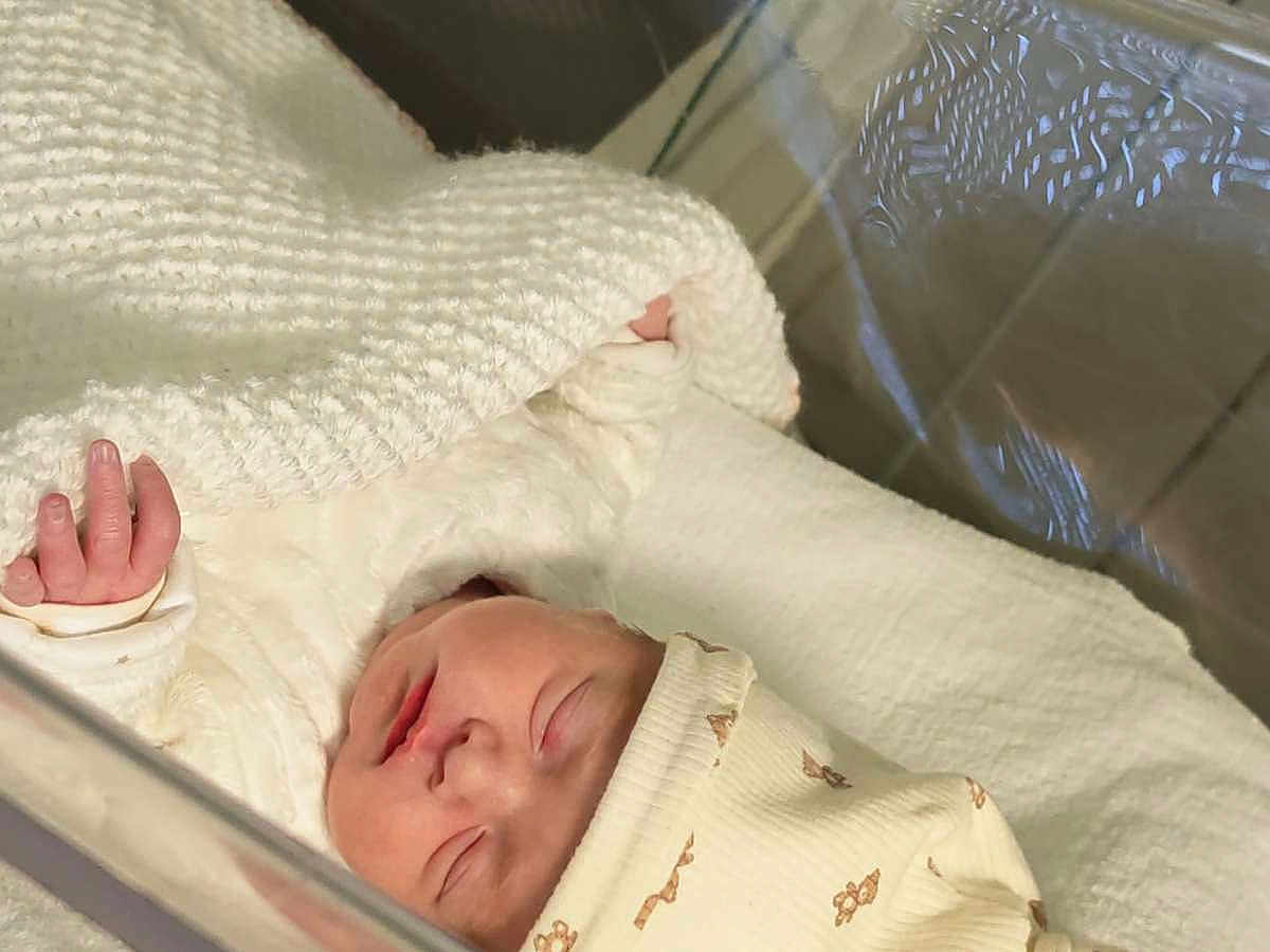 Eily a rejoint le concours — aidez-le/la à gagner de superbes lots ! baby, newborn, sleeping, bassinet, blanket, swaddle, hat, infant, hand, face, peaceful, cozy, hospital, closeup, soft_light, white_texture, crib, tiny, portrait, newborn_bed