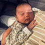 Victoire participe au concours pour gagner de l'argent avec cette photo : baby, sleeping, infant, person, arms, floral_clothing, soft_lighting, closeup, peaceful, hand, striped_fabric, toddler, skin, face, newborn, cute, cozy, indoor, holding, portrait
