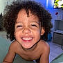 child, smiling, curly_hair, happy, indoors, portrait, face, skin, person, young_child, tooth, bare_shoulders, expression, cheerful, closeup, home, couch, room, lighting, joy