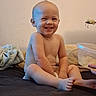 baby, child, infant, smiling, sitting, bed, bedroom, blanket, diaper, bare_chested, portrait, face, teeth, happy, indoor, home, container, toy, wall, photography