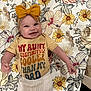 Marymae joined the competition — help win amazing prizes! baby, smiling, bow, headband, shirt, text_on_clothing, floral_pattern, blanket, lying_down, infant, cute, happy, child, indoors, toddler, clothing, person, bright_colors, fabric, portrait