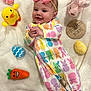 baby, infant, smiling, onesie, bow_headband, plush_toy, stuffed_animal, chick, bunny, carrot, easter_egg, wooden_plaque, blanket, colorful, cute, lying_down, indoors, soft_texture, four_months, celebration