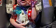 Jesse is registered to the contest to win money with this photo: baby, infant, car_seat, clothing, suspenders, bow_tie, hand, face, expression, seat, striped_shorts, buttoned_shirt, comfort, child, cute, indoor, young, padded, safety, person