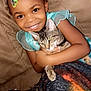 child, cat, couch, blanket, smiling, happy, indoor, beads, hair, arm, pet, tabby_cat, furniture, cozy, closeup, portrait, holding, warm, comfort, cute