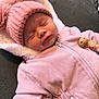 baby, sleeping, pink_hat, knitted_hat, pom_poms, pink_outfit, zipper, blanket, soft_texture, infant, child, cute, peaceful, warm_clothing, indoor, portrait, newborn, resting, cozy, adorable