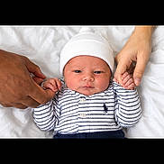 Keshawn joined the competition — help win amazing prizes! newborn, baby, infant, child, portrait, lying_down, white_bedding, bed, knit_hat, striped_clothing, onesie, long_sleeves, hands, adult_hands, family, indoor, close_up, face, awake, safe