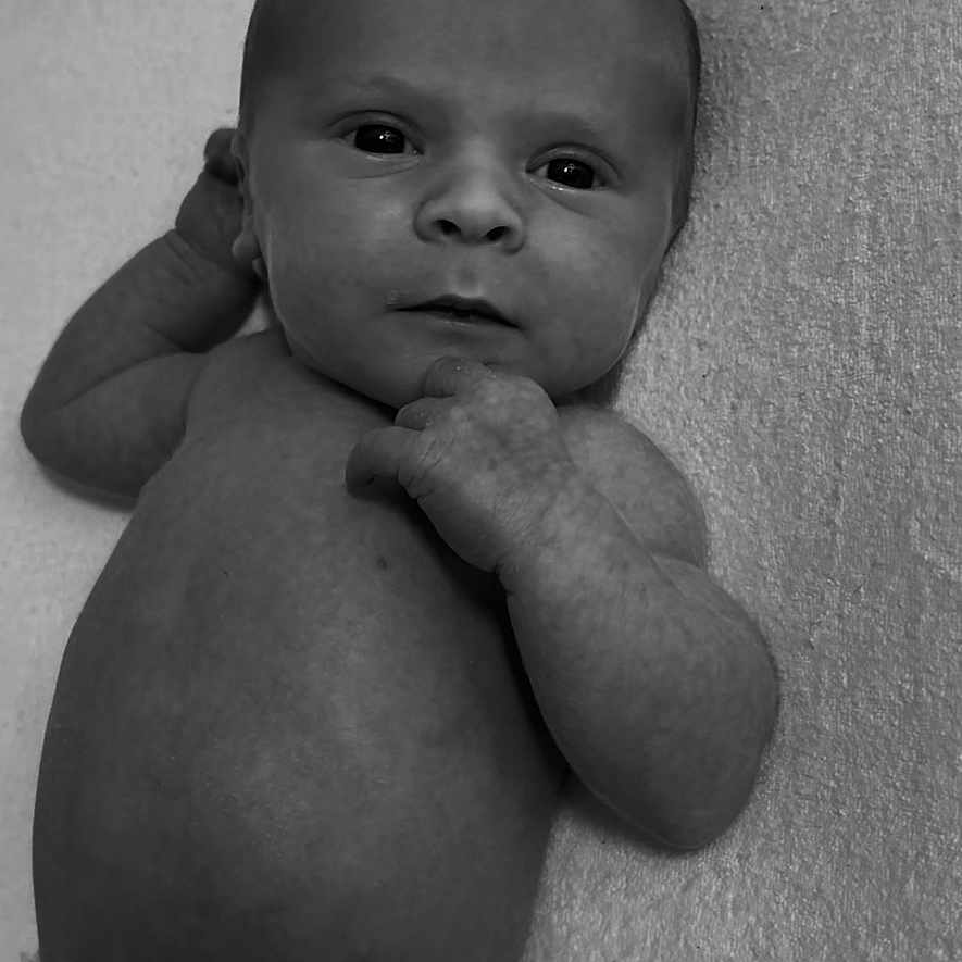 Frankie-Junior is registered to the contest to win money with this photo: baby, black_and_white, child, closeup, curious, cute, diaper, expression, face, hand, human, infant, lying_down, monochrome, newborn, portrait, skin, small, soft, texture