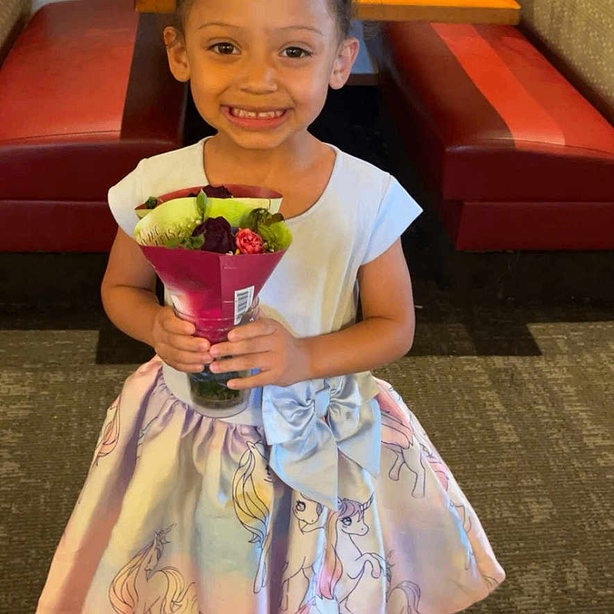 Katari is registered to the contest to win money with this photo: booth_seating, bow, carpet, celebration, child, clothing, cute, dress, flower_bouquet, girl, hair, happy, holding, indoor, person, portrait, restaurant, smile, table, unicorn