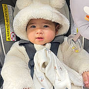 Micah is registered to the contest to win money with this photo: baby, infant, car_seat, fluffy_hoodie, bear_ears, blanket, cute, child, clothing, seatbelt, portrait, indoor, soft_texture, smiling, face, hand, toy, comfort, warm_clothing, adorable