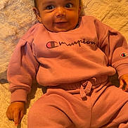 Leila joined the competition — help win amazing prizes! baby, child, smile, pink_clothing, sweatshirt, sweatpants, champion_brand, face, eyes, hand, blanket, bed, indoor, cute, infant, person, portrait, happy, cozy, soft