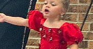 black_clothing, brick_wall, calvin_klein, celebration, child, cute, dance, dress_tag, earrings, girl, hair_bow, indoor, motion, performance, person, portrait, puffy_sleeves, red_dress, sparkly, young