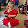 bag, blurred_background, bow, child, costume, cute, dance, dress_up, event, fashion, floor, footwear, indoor, pageant, person, portrait, red_dress, smile, tutu, young_girl