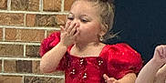 Legacy is registered to the contest to win money with this photo: blowing_kiss, bow, brick_wall, celebration, child, cute, event, fashion, girl, hand_gesture, happy, indoor, number_card, pageant, person, portrait, red_dress, sitting, sparkle, young
