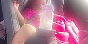 Lazaharia Roddie is registered to the contest to win money with this photo: baby, blanket, bottle, car_interior, car_seat, child, clothing, foot, hand, infant, pink, relaxing, safety, seat, seatbelt, sleeping, sunlight, toddler, travel, window