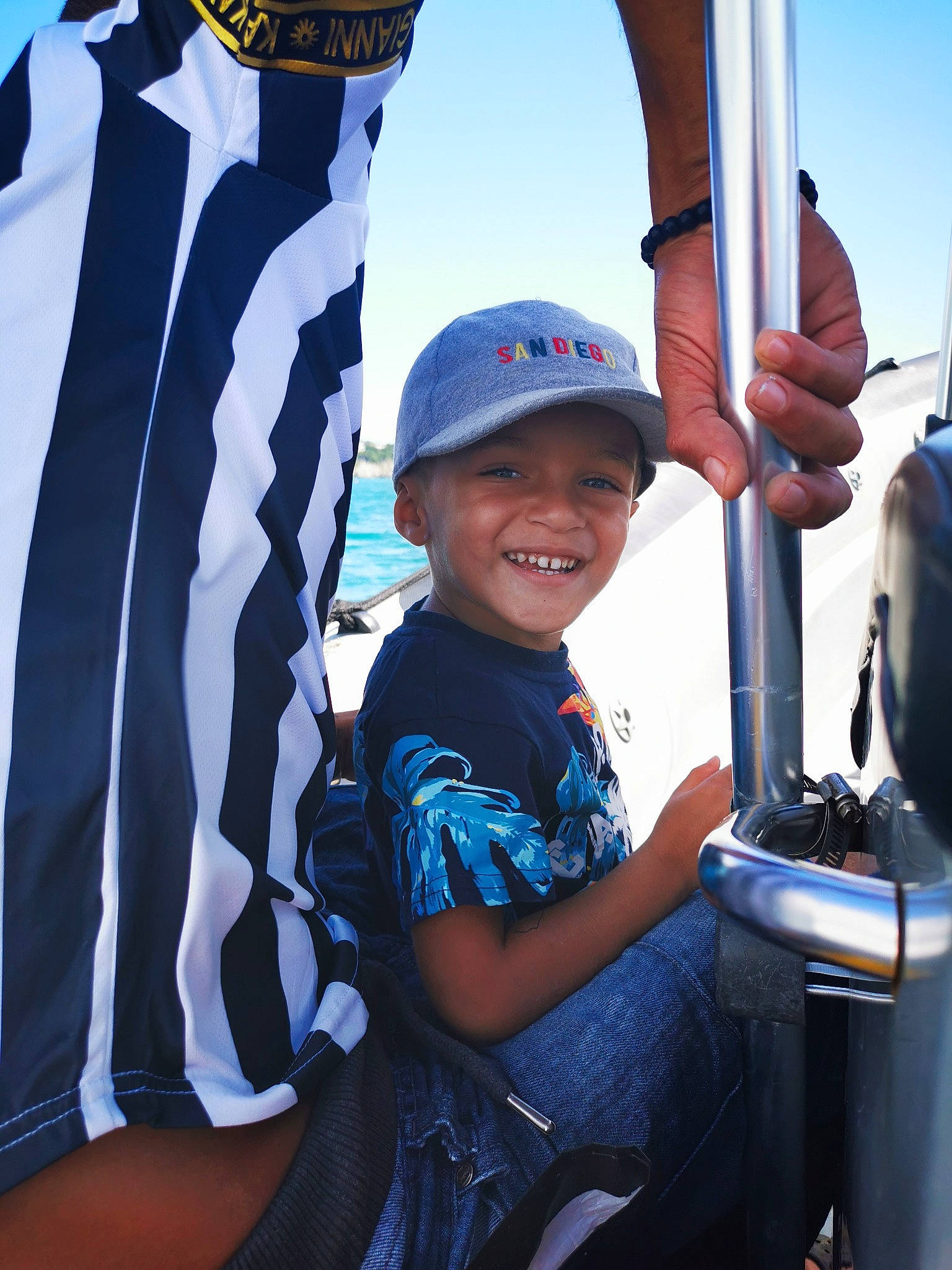 Diego a rejoint le concours — aidez-le/la à gagner de superbes lots ! automotive_tire, baseball_cap, boats_and_boating_equipment_and_supplies, cap, child, elbow, electric_blue, flag, fun, happy, headwear, joy, leisure, person, product, recreation, shorts, sky, sleeve, smile