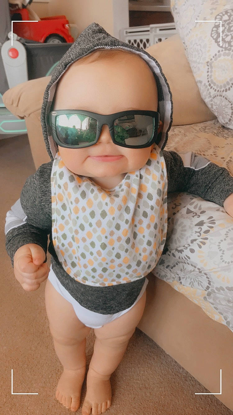 Damon is registered to the contest to win money with this photo: audio_equipment, baby, baby_toddler_clothing, child, comfort, design, eyewear, fun, glasses, goggles, moustache, outerwear, pattern, person, personal_protective_equipment, sleeve, sunglasses, thigh, toddler, vision_care