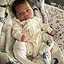 baby, infant, pajamas, blanket, halloween, spiders, crescent_moon, stars, face, curly_hair, clothing, lying_down, soft_texture, pattern, cozy, indoor, person, newborn, cute, sleepwear