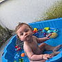 toddler, child, pool, water, toys, blue_pool, bath_toys, curly_hair, wet_skin, outdoor, concrete_floor, moss, plastic, sitting, playtime, summer, bath, baby, cute, curious