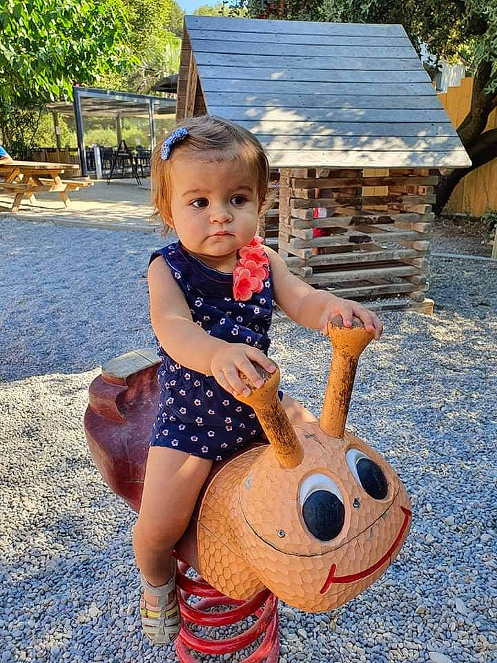 Meryl a rejoint le concours — aidez-le/la à gagner de superbes lots ! art, baby_toddler_clothing, blue, child, fun, grass, happy, house, human_leg, leisure, musical_instrument, people, people_in_nature, person, public_space, recreation, sitting, string_instrument, summer, thigh