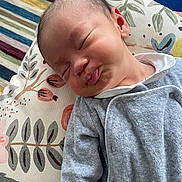 Félix participe au concours pour gagner de l'argent avec cette photo : baby, infant, pout, face, expression, onesie, clothing, cushion, floral_pattern, carpet, striped_rug, indoor, cute, sleepy, child, newborn, soft_texture, portrait, cozy, funny_expression