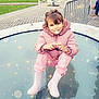 building, casual, child, cute, daylight, fence, glass_surface, outdoor, pacifier, people, pink_jacket, playful, posing, rain_boots, reflection, sparkles, street, toddler, urban, winter_clothing