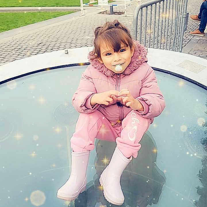 Illanna a rejoint le concours — aidez-le/la à gagner de superbes lots ! building, casual, child, cute, daylight, fence, glass_surface, outdoor, pacifier, people, pink_jacket, playful, posing, rain_boots, reflection, sparkles, street, toddler, urban, winter_clothing